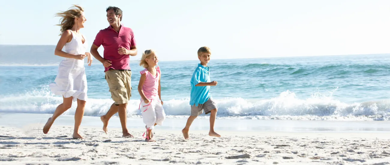 A family running together along a sunny beach